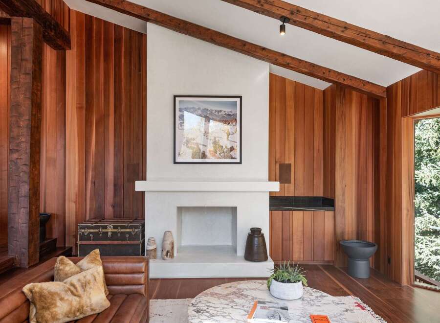 This stunning living room boasts a cozy fireplace framed by a white mantel, set against a rich wood-paneled wall.
