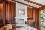 This stunning living room boasts a cozy fireplace framed by a white mantel, set against a rich wood-paneled wall.