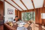 This stunning living room boasts a cozy leather sectional sofa, perfectly positioned to enjoy the expansive window views of the lush forest.