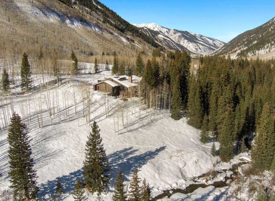 This secluded mountain home boasts stunning views and a tranquil setting nestled amongst snow-covered evergreens.