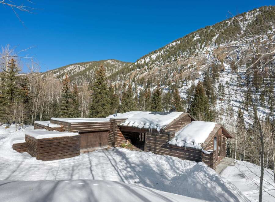 This stunning log cabin nestled in the Colorado mountains boasts a spacious design with a large garage and expansive windows offering breathtaking views.