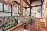 This stunning home boasts a grand entrance with a striking combination of natural wood beams, a rustic stone wall, and a sleek glass railing.