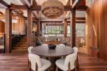 This stunning home boasts a spacious dining area with a large, round wooden table surrounded by cozy white chairs, creating a warm and inviting atmosphere.