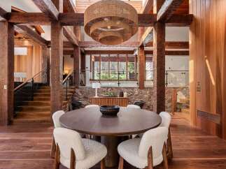 This stunning home boasts a spacious dining area with a large, round wooden table surrounded by cozy white chairs, creating a warm and inviting atmosphere.