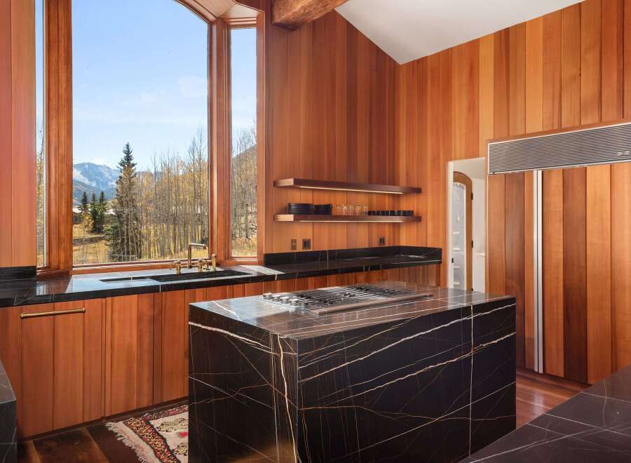 This stunning kitchen boasts a large island with a black marble countertop and a built-in gas cooktop, perfect for entertaining.