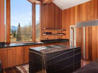 This stunning kitchen boasts a large island with a black marble countertop and a built-in gas cooktop, perfect for entertaining.