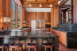 This stunning kitchen boasts a large island with dark marble countertops and wooden stools, perfect for casual dining.