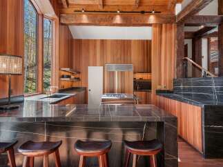 This stunning kitchen boasts a large island with dark marble countertops and wooden stools, perfect for casual dining.