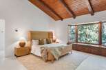 This bedroom boasts a stunning wooden beam ceiling and large bay window overlooking a lush green landscape.