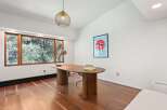 This modern home office boasts a stunning walnut wood floor, large windows offering abundant natural light, and a sleek, mid-century modern desk.