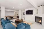 This stunning modern home boasts a spacious game room with a ping pong table, plush sectional sofa, and a cozy fireplace.