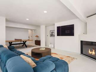 This stunning modern home boasts a spacious game room with a ping pong table, plush sectional sofa, and a cozy fireplace.