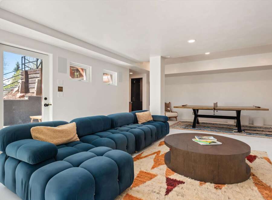 This stunning basement boasts a spacious, open layout perfect for entertaining, featuring a plush sectional sofa and a stylish coffee table.
