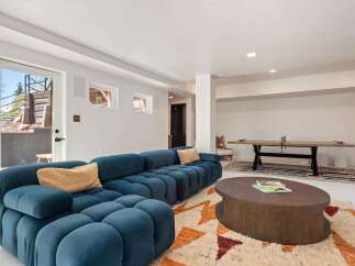 This stunning basement boasts a spacious, open layout perfect for entertaining, featuring a plush sectional sofa and a stylish coffee table.