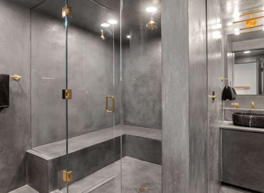 This luxurious bathroom boasts a spacious shower with a built-in bench, enclosed by sleek glass walls and featuring modern gold fixtures.