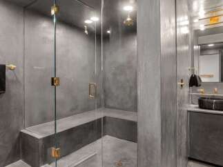 This luxurious bathroom boasts a spacious shower with a built-in bench, enclosed by sleek glass walls and featuring modern gold fixtures.