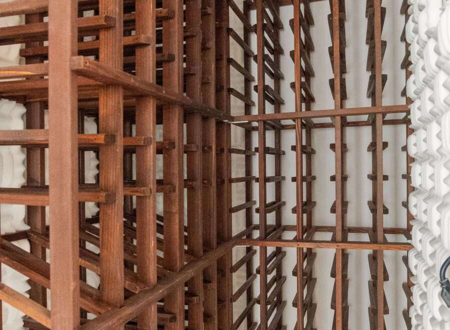 This stunning wine cellar boasts two expansive wooden racks, offering ample storage for an impressive collection.
