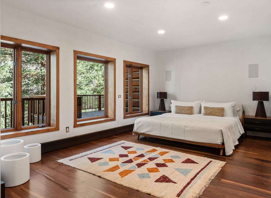 This stunning bedroom boasts a minimalist design with large windows offering breathtaking views of the surrounding landscape.