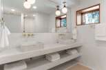 This stunning bathroom boasts a double vanity with marble sinks, sleek gold fixtures, and built-in shelving for added convenience.