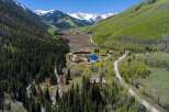 Nestled in a stunning mountain valley, this secluded property boasts multiple buildings, including a large main lodge and several smaller cabins.