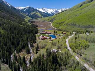 Nestled in a stunning mountain valley, this secluded property boasts multiple buildings, including a large main lodge and several smaller cabins.