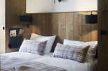 Cozy up in this charming bedroom featuring a rustic wooden wall, plush bedding, and a unique deer head mount.