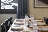 This stunning chalet boasts a large dining table perfect for family gatherings, complete with modern tableware and a breathtaking view of the snowy mountains.