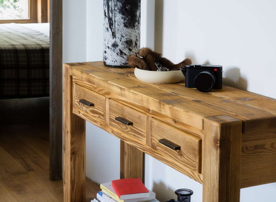Rustic wooden console table with three drawers, perfect for entryway storage.