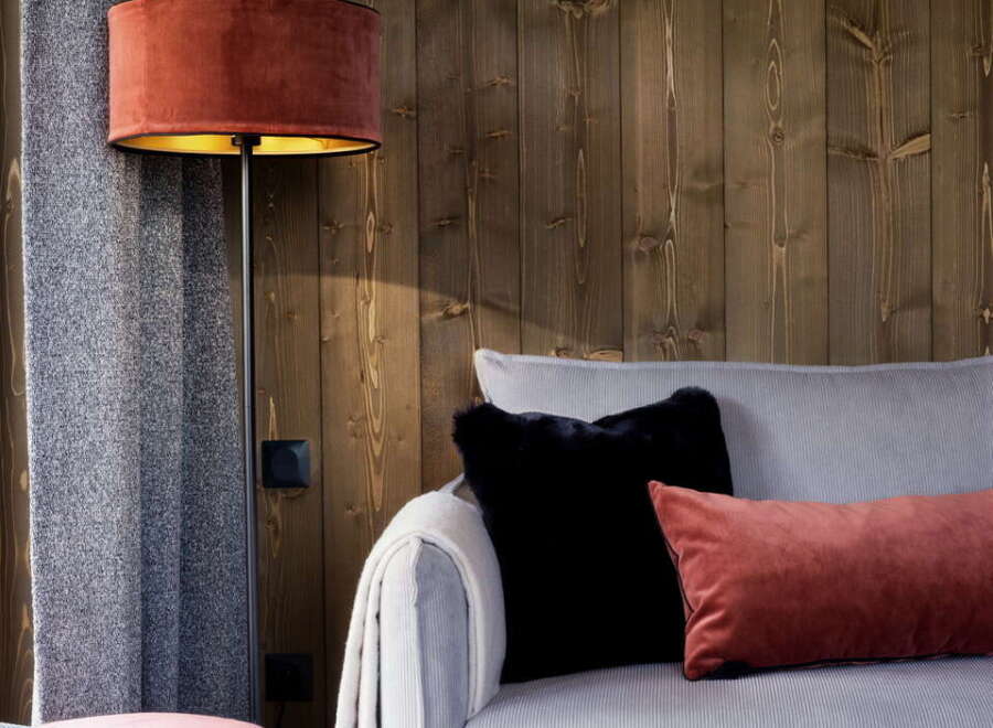 Cozy living room with a light grey corduroy sofa, complemented by plush red and black velvet cushions.