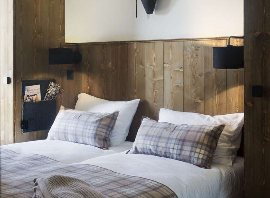 Cozy up in this charming bedroom featuring a rustic wooden wall, plush bedding, and a unique deer head mount.