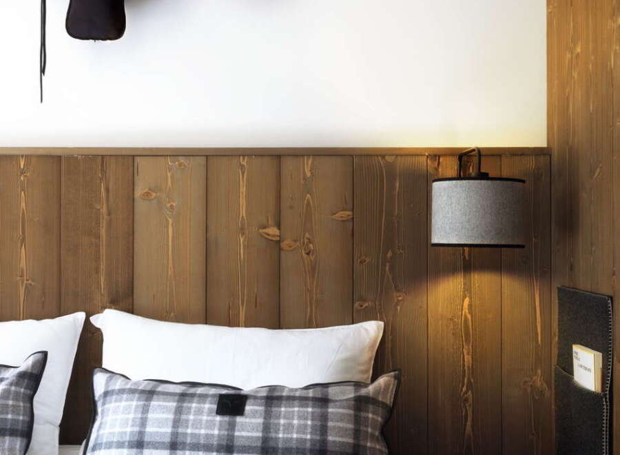 Cozy up in our rustic-chic room, featuring a plush bed with plaid accents and a unique longhorn skull wall decoration.