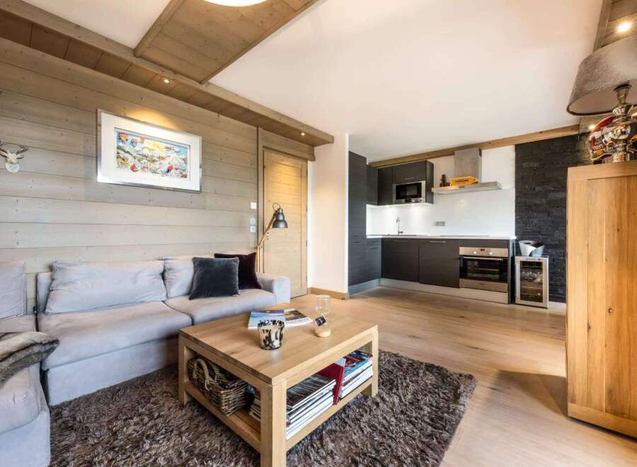 This stunning apartment boasts a cozy living area with a light grey sectional sofa, perfect for relaxing after a day on the slopes.