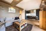 This stunning apartment boasts a cozy living area with a light grey sectional sofa, perfect for relaxing after a day on the slopes.