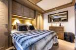 Cozy chalet bedroom with built-in wooden wardrobes and a plush fur throw on the bed.