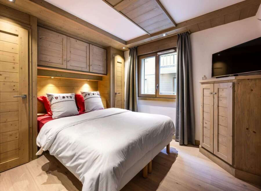 Cozy chalet bedroom with built-in wooden wardrobes and a comfortable double bed.