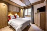 Cozy chalet bedroom with built-in wooden wardrobes and a comfortable double bed.