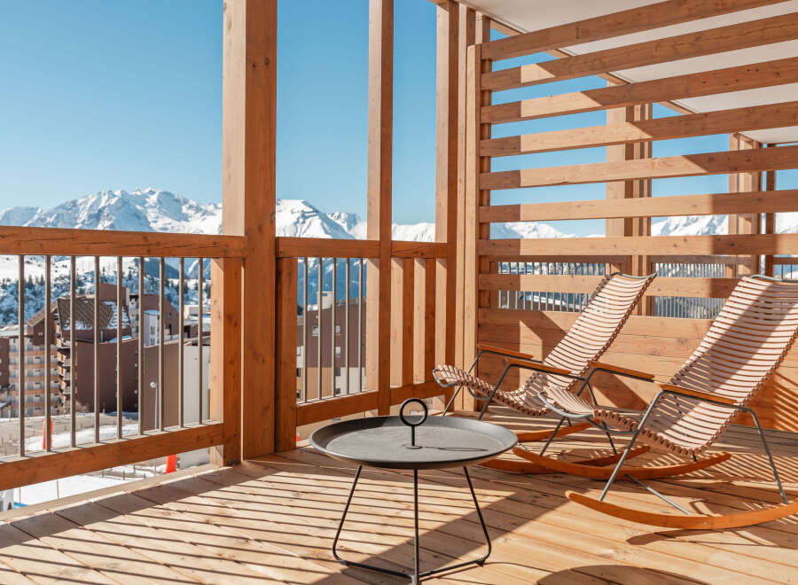 Relax and enjoy breathtaking mountain views from your private balcony, complete with comfortable rocking chairs and a stylish side table.