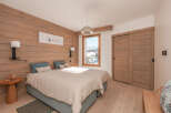 Cozy twin bedroom with wood-paneled walls and a view of the snowy mountains.