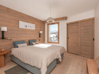 Cozy twin bedroom with wood-paneled walls and a view of the snowy mountains.
