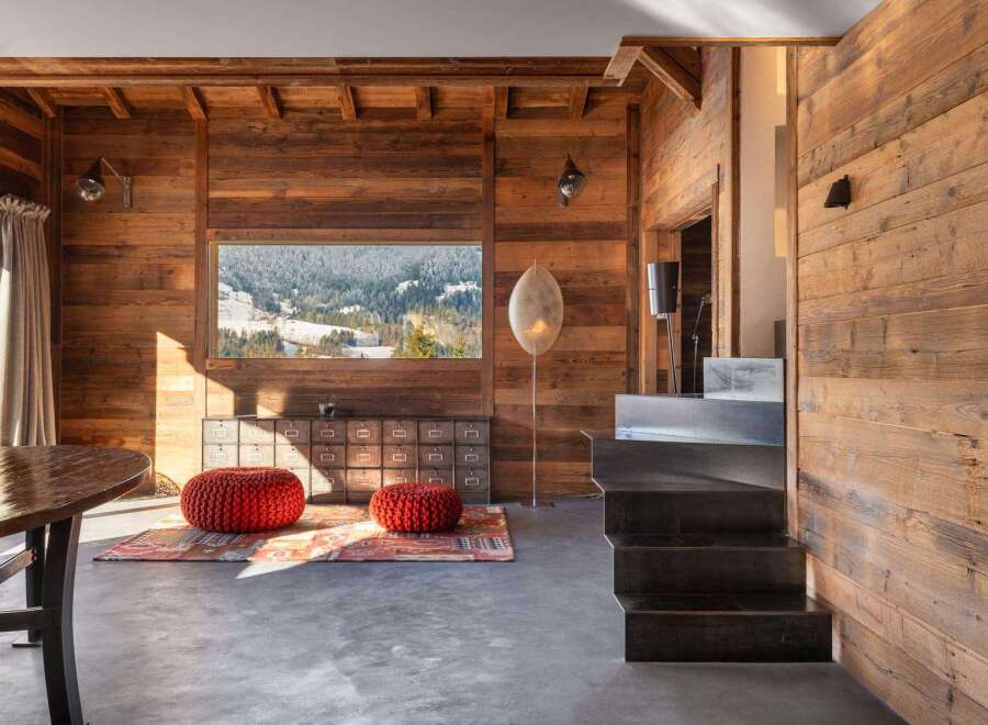This stunning chalet boasts a rustic-chic interior with exposed wooden beams and walls, creating a warm and inviting atmosphere.