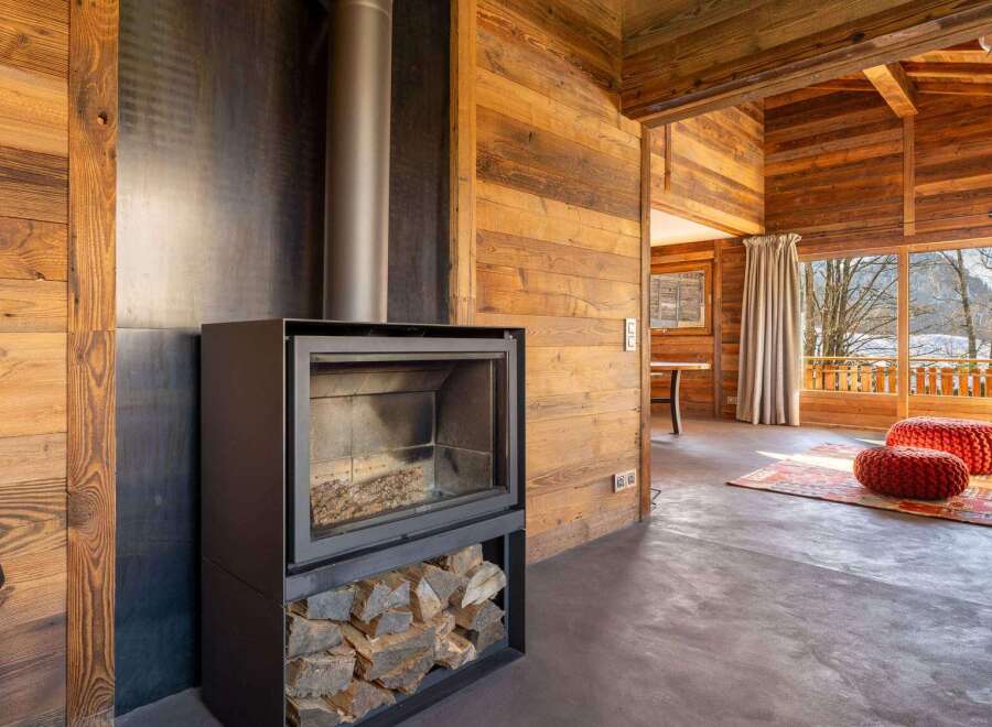 This stunning chalet boasts a modern wood-burning stove, perfectly complementing the rustic wooden interior.