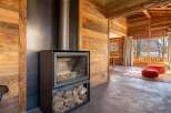 This stunning chalet boasts a modern wood-burning stove, perfectly complementing the rustic wooden interior.