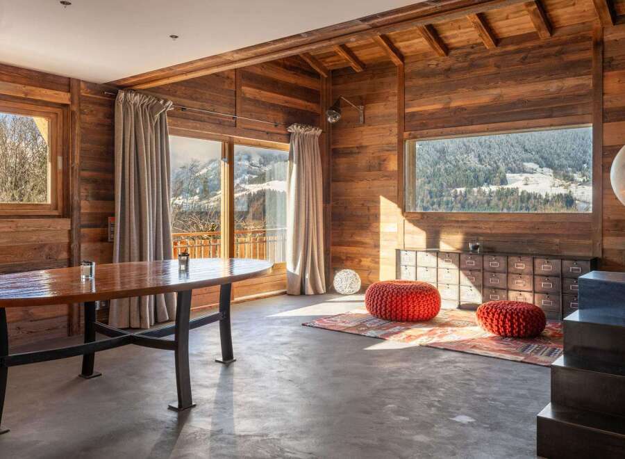 This stunning chalet boasts a spacious open-plan living area with floor-to-ceiling windows offering breathtaking mountain views.