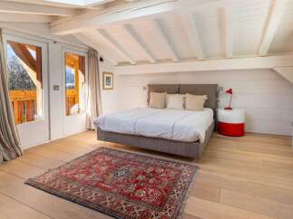 This stunning bedroom boasts a cozy atmosphere with its rustic wooden beams and large windows offering breathtaking views.