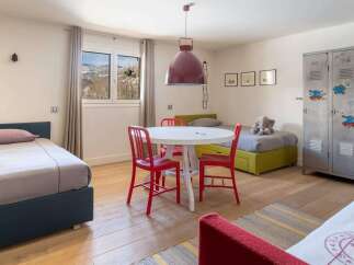 Stylish kids' bedroom with twin beds, a playful metal locker, and a bright, airy atmosphere.
