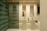 This luxurious bathroom boasts a stunning green tile shower, complemented by sleek, minimalist sinks and mirrors.