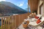Mountain view balcony with wooden furniture and cozy seating.