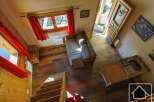 This charming chalet boasts a cozy open-plan living area with a comfortable sofa and a rustic wooden kitchenette.