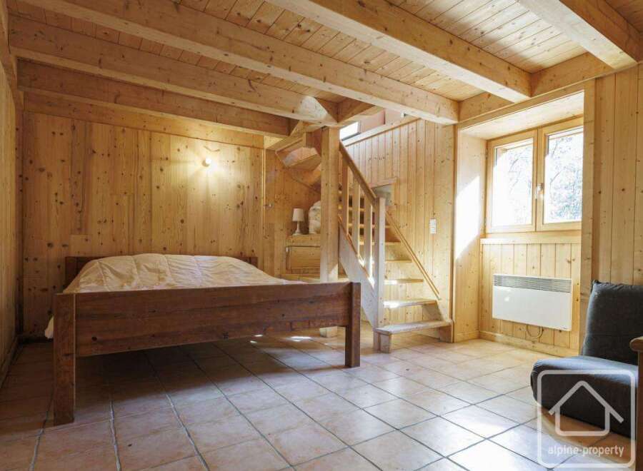 This charming wooden chalet bedroom features a rustic double bed, tiled floors, and a cozy atmosphere.