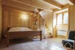 This charming wooden chalet bedroom features a rustic double bed, tiled floors, and a cozy atmosphere.